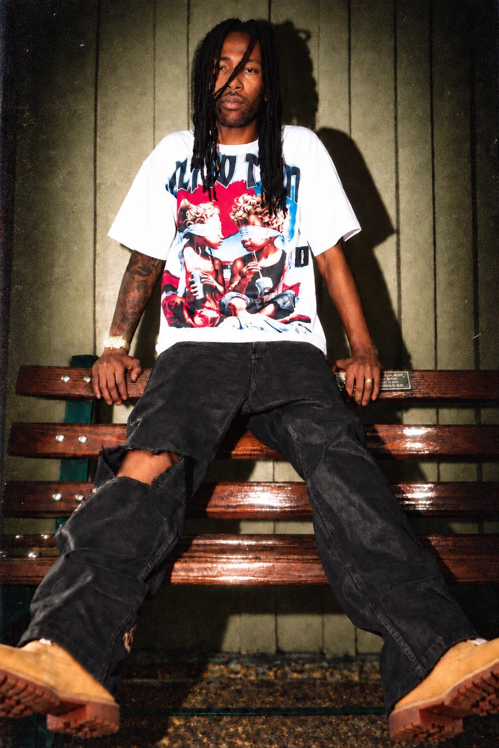 VTILTED Fall 2 drop - model in graphic tee on a bench